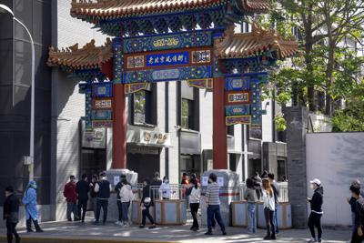 Gente con mascarilla hace fila para hacerse pruebas de coronavirus en un vecindario en el distrito de Dongcheng, Beijing, el martes 26 de abril de 2022. (AP Foto/Mark Schiefelbein)