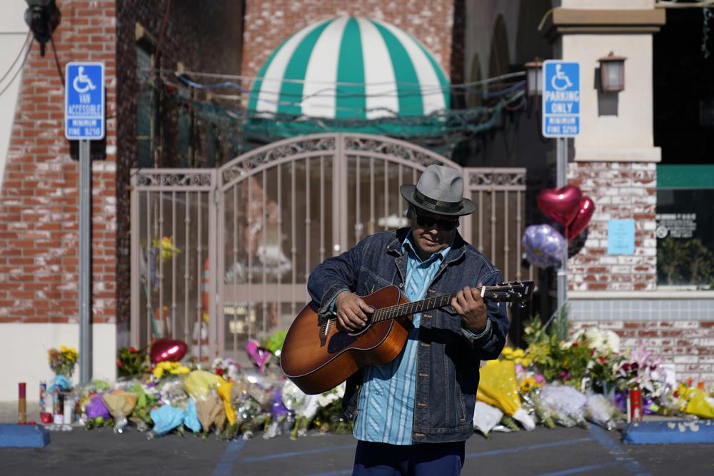 Gabriel Alexander plays a guitar and sings near a memorial outside the Star Ballroom Dance Studio on Tuesday, Jan. 24, 2023, in Monterey Park, Calif. A gunman killed multiple people at the ballroom dance studio late Saturday amid Lunar New Years celebrations in the predominantly Asian American community. (AP Photo/Ashley Landis)