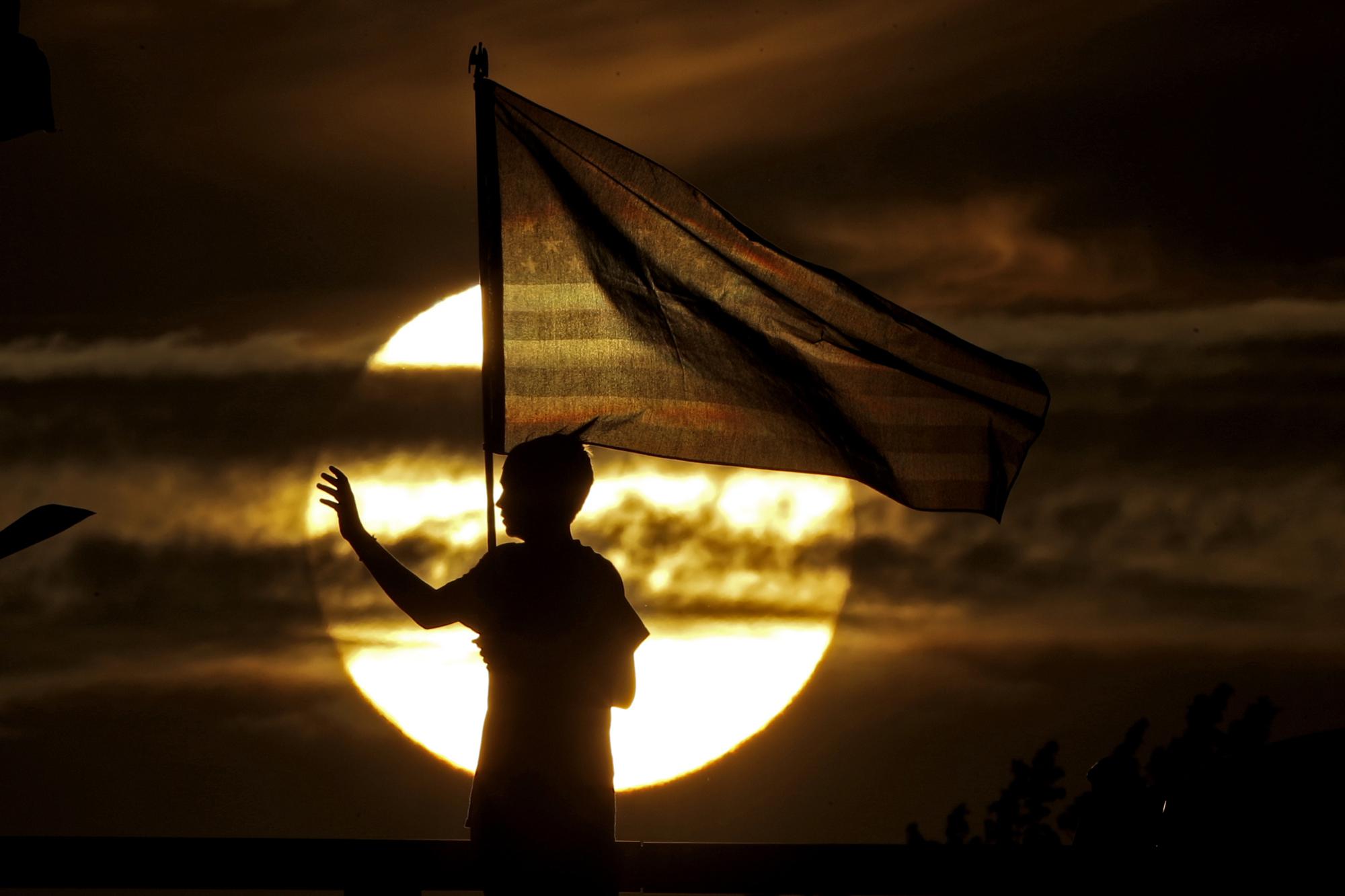 ADVANCE FOR PUBLICATION ON SUNDAY, SEPT. 5, AND THEREAFTER - FILE - In this Wednesday, Sept. 11, 2019 file photo, a boy waves to passing motorists to commemorate the anniversary of the Sept. 11 terrorist attacks from an overpass on Interstate 35 near Melvern, Kan. Area residents began manning the bridge with flags and waving to motorists on the anniversary in 2002 and have done it ever since. (AP Photo/Charlie Riedel, File)