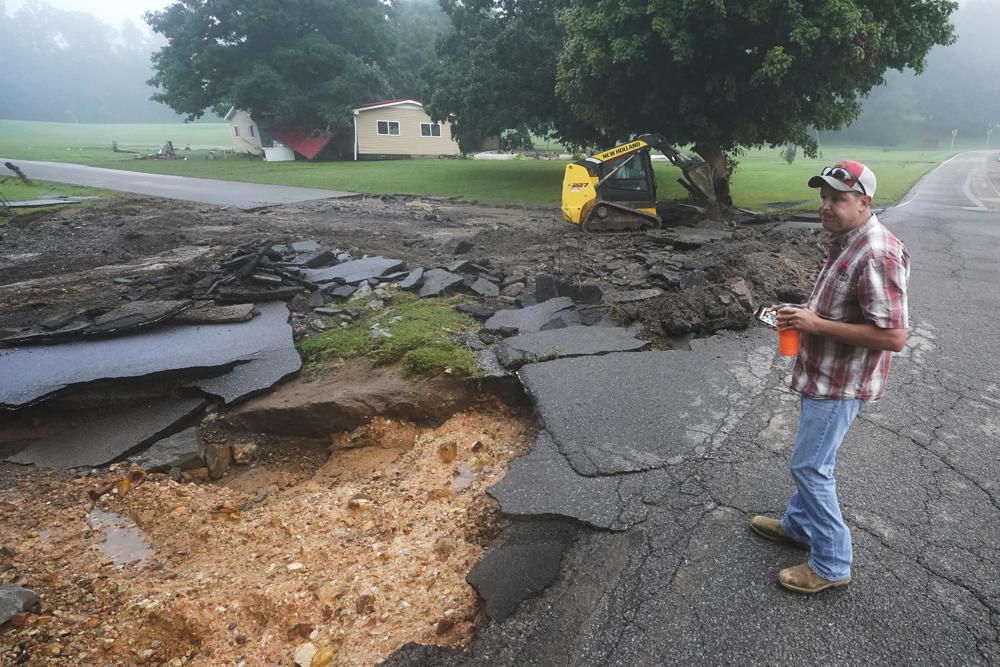 CORRECTS ID TO MICHAEL PATE NOT WAYNE SPEARS. Michael Pate watches as a road is repaired Sunday, Aug. 22, 2021, in McEwen, Tenn. Pate repaired the road Saturday after heavy rain washed part of it away, but the road was damaged again when more rain fell Saturday night. Heavy rains caused flooding in Middle Tennessee and have resulted in multiple deaths as homes and rural roads were washed away. (AP Photo/Mark Humphrey)