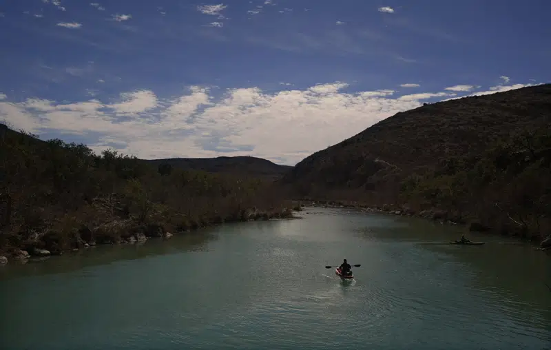 A paddler floats along the Devil's River, Friday, Feb. 17, 2023, near Del Rio, Texas. Some landowners along the Devil's River argue that proposed wind turbines would kill birds, bats and disrupt monarch butterflies migrating to Mexico and impact ecotourism, a main source of income for many. (AP Photo/Eric Gay)