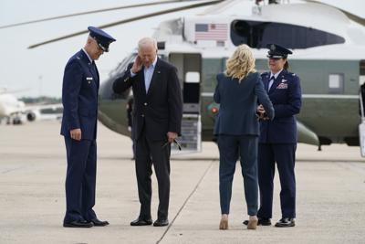 El presidente Joe Biden se quita una cigarra del cuello mientras se prepara junto con su esposa Jill Biden para abordar el avión oficial Air Force One, el miércoles 9 de junio de 2021. (AP Foto/Patrick Semansky)