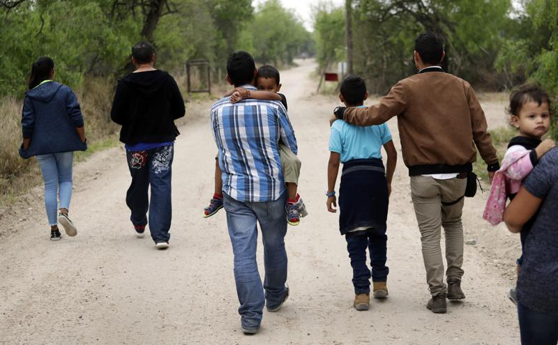 FILE - A group of migrant families walk from the Rio Grande, the river separating the U.S. and Mexico in Texas, near McAllen, Texas, March 14, 2019. A Biden administration effort to reunite children and parents who were separated under President Donald Trump's zero-tolerance border policy has made increasing progress as it nears the end of its first year. The Department of Homeland Security planned Thursday, Dec. 23, to announce that 100 children, mostly from Central America, are back with their families and about 350 more reunifications are in process after it adopted measures to enhance the program. (AP Photo/Eric Gay, File)