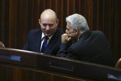 El líder del partido Yamina, Naftali Bennett (izquierda), sonríe mientras habla con el de Yesh Atid, Yair Lapid, durante una sesión extraordinaria en el Knesset, el parlamento israelí, en Jerusalén, el 2 de junio de 2021. (Ronen Zvulun/Pool Photo via AP)
