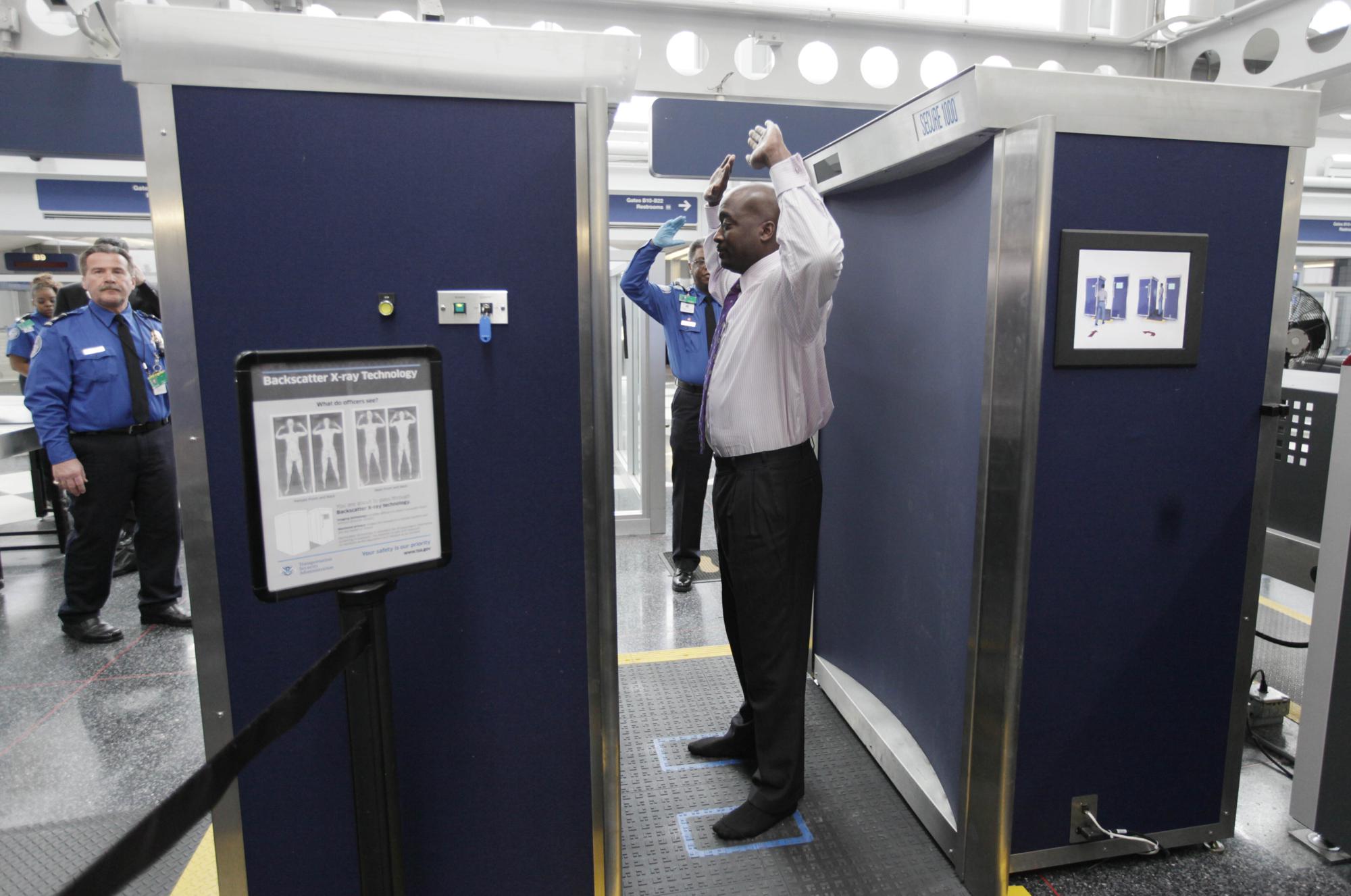 FILE - In this March 15, 2010 file photo, a volunteer passes through the first full body scanner installed at O'Hare International Airport in Chicago. The technology produces a cartoon-like outline rather than naked images of passengers by using X-rays. (AP Photo/M. Spencer Green, File)