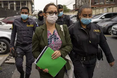 ARCHIVO - La exfiscal guatemalteca Virginia Laparra es escoltada por la policía cuando llega a la corte para una audiencia en la Ciudad de Guatemala, el martes 7 de junio de 2022. La exfiscal ha pasado un año en la cárcel condenada por abuso de poder por denunciar a un juez que filtró información en un caso de corrupción. (AP Foto/Moisés Castillo, Archivo)