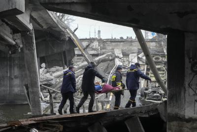 Rescatistas ucranianos cargan a una mujer debajo de un puente destruido en Irpín, Ucrania, el viernes 1 de abril de 2022. (AP Foto/Efrem Lukatsky)