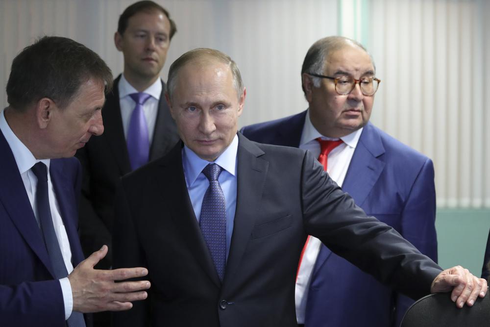 FILE - Russian President Vladimir Putin, center, listens to Lebedinsky GOK Managing Director Oleg Mikhailov, left, as businessman and founder of USM Holdings, Alisher Usmanov, right, and Minister of Industry and Trade Denis Manturov stand behind him while visiting the Lebedinsky GOK JSC, in Gubkin, Belgorod Region, Russia, Friday, July 14, 2017. Usmanov is not on the sanctions list implemented in response to the 2022 invasion of Ukraine. The metals tycoon was an early investor in Facebook. His fortune is estimated at more than $14 billion.  (Mikhail Klimentyev/Sputnik/Kremlin Pool Photo via AP, File)