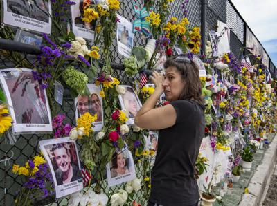 Gini Gonte visita el miércoles 7 de julio de 2021 un muro con fotografías y flores para recordar a las víctimas del desplome del edificio residencial Champlain Towers South, en Surfside, Florida. (Al Diaz/Miami Herald vía AP)