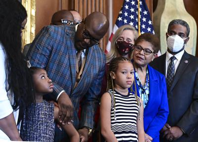 Philonise Floyd, hermano de George Floyd, mira a la hija de éste, Gianna Floyd, rodeados por otros miembros de la familia al conmemorar el 1er aniversario del asesinato de George Floyd junto con la presidenta de la cámara Nancy Pelosi en el Capitolio, Washington, martes 25 de mayo de 2021. (Erin Scott/Pool via AP)