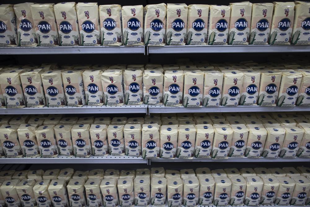 A shelf is full of corn and rice flour at supermarket in Caracas, Venezuela, Friday, June 4, 2021. Two years ago Venezuela stopped restricting transactions in dollars which has largely ended shortages that for years left markets with chronically empty shelves, but has meant many Venezuelans who are paid in bolivars can't afford what's on those shelves. (AP Photo/Ariana Cubillos)