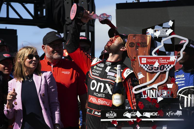 El mexicano Daniel Suárez festeja su victoria bebiendo vivo en la NASCAR Cup Series en Sonoma, California, el domingo 12 de junio de 2022. (AP Foto/D. Ross Cameron)