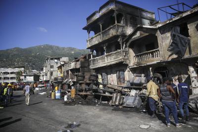 Bomberos están parados junto a los restos de un camión que trasportaba gasolina después que volcó y estalló en Cabo Haitiano, Haití, martes 14 de diciembre de 2021. (AP Foto/Joseph Odelyn)