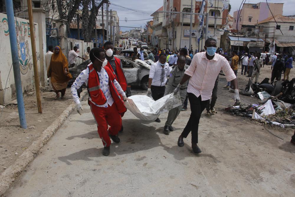 Medical personnel carry a body after a car bomb attack at a Presidential Palace checkpoint in Mogadishu, Somalia, Saturday Sept. 25, 2021. Police said a vehicle laden with explosives rammed into cars and trucks at a checkpoint leading to the entrance of the Presidential Palace, killing at least eight people. (AP Photo/Farah Abdi Warsameh)