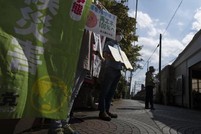 Miembros de Kodaira Solar sostienen carteles durante una manifestación para promover plantas de energía solar en la comunidad, en el exterior de la estación de tren de Kodaira, al oeste de Tokio, el 24 de septiembre de 2021. (AP Foto/Hiro Komae)