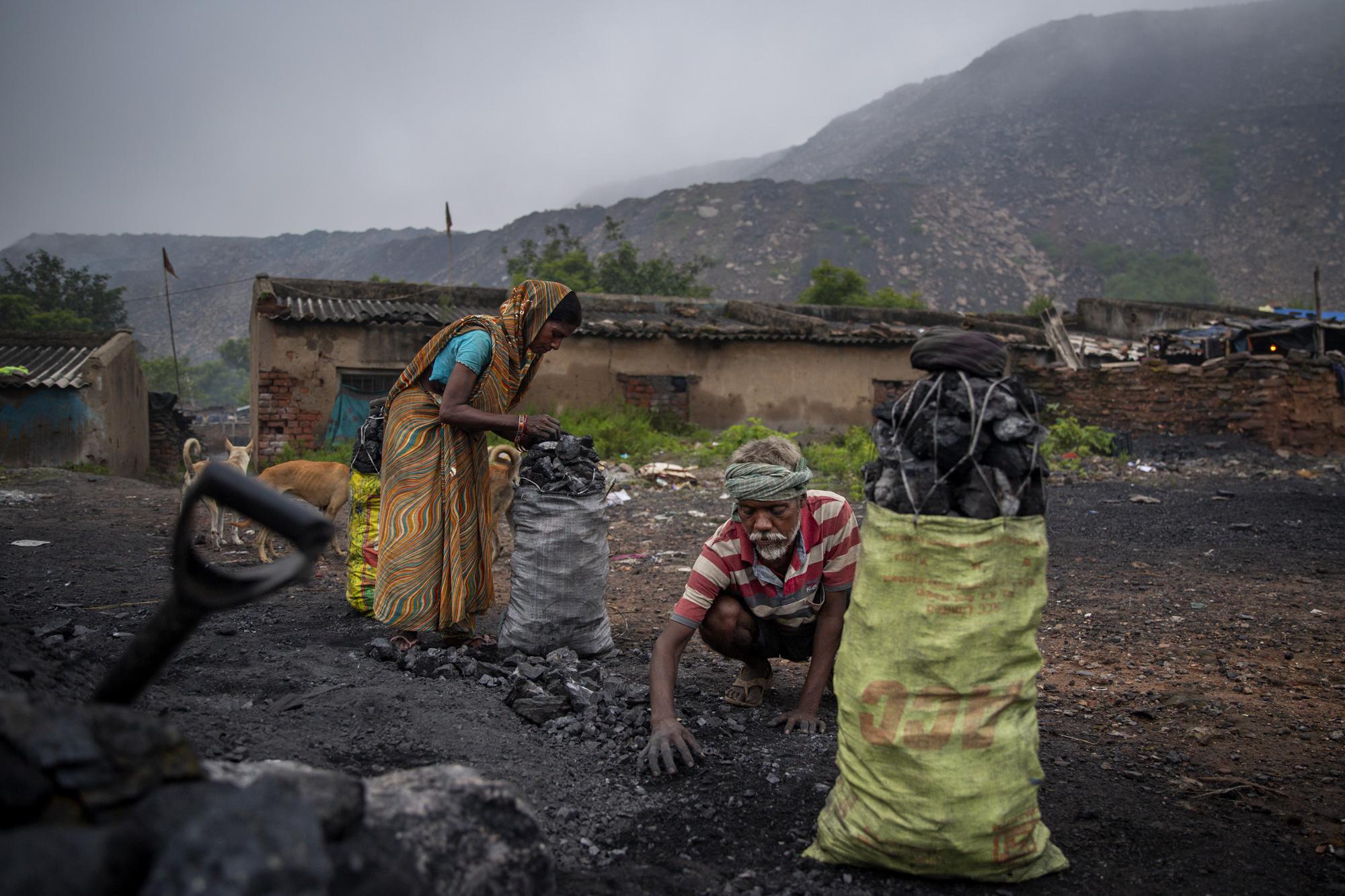 Naresh Chauhan, 50, his wife Rina Devi, 45 fill sacks with coal in Dhanbad, an eastern Indian city in Jharkhand state, Friday, Sept. 24, 2021. The two have lived in a village at the edge of the Jharia coalfield in Dhanbad all their lives. The couple earn $3 a day selling four baskets of scavenged coal to traders. For people like Chauhan and Devi, India’s economic slowdown resulting from the pandemic has intensified their dependence on coal. (AP Photo/Altaf Qadri)