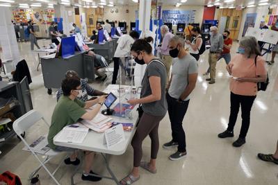 ARCHIVO - Votantes inscribiéndose en la escuela secundaria Frank McCourt para las primarias de partidos en Nueva York, el 22 de junio de 2021 en Nueva York. (AP Foto/Richard Drew, Archivo)