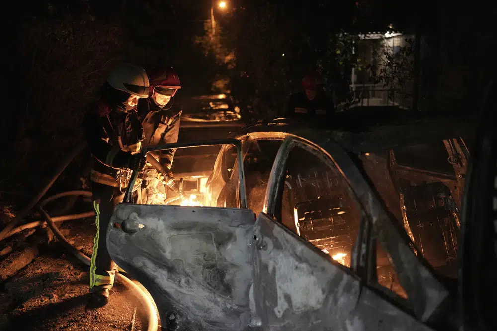 Socorristas tratan de apagar un auto que se incendió por la caída de escombros tras un ataque aéreo ruso en el distrito de Pecherskyi, en Kiev, Ucrania, el martes 30 de mayo de 2023. (AP Foto/Roman Hrytsyna)