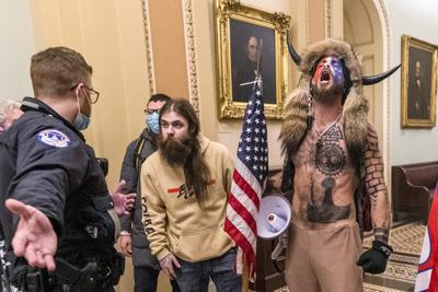 ARCHIVO En esta foto del 6 de enero del 2021, partidarios del presidente Donad Trump, incluyendo Jacob Chansley, derecha con un gorro con cuernos, son confrontados por un policía del Capitolio en las afueras de la sala del Senado en el Senado. Falsedades sobre la elección presidencial contribuyeron al asalto al Capitolio y algunos de los que ahora son enjuiciados por sus acciones entonces esperan que su candidez ayude a salvarles o al menos genere alguna simpatía. (AP Foto/Manuel Balce Ceneta, Archivo)
