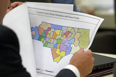 ARCHIVO - En esta imagen del 26 de julio de 2017, un legislador estudia un mapa distrital durante una reunión de una comisión conjunta sobre la redistribución de distritos electorales, en Raleigh, Carolina del Norte. (AP Foto/Gerry Broome, archivo)