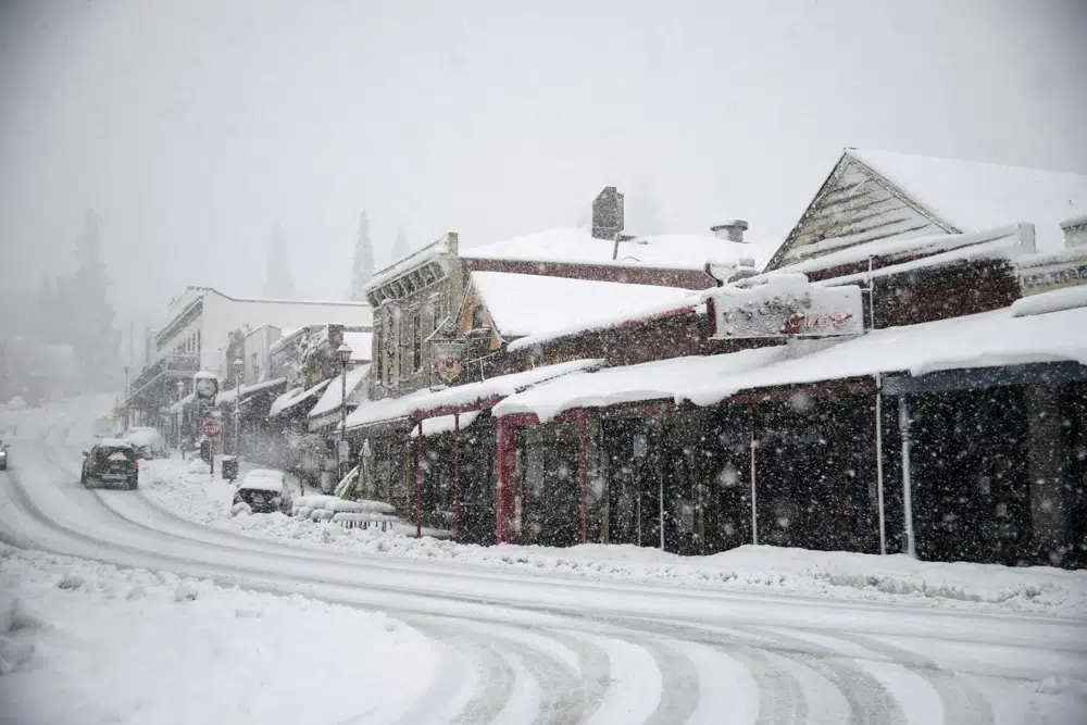Los vehículos avanzan por Main Street a través de una fuerte nevada en Grass Valley, California, el martes 28 de febrero de 2023. (Elias Funez/The Union vía AP)