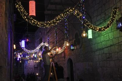 Un palestino coloca una guirnalda de luces como parte de los preparativos para la celebración del mes sagrado del islam, el ramadán, en una calle de la Ciudad Vieja de Jerusalén, el 1 de abril de 2022. (AP Foto/Mahmoud Illean)