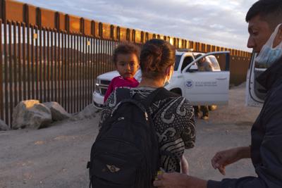 ARCHIVO - En esta fotografía de archivo del 10 de junio de 2021, una familia migrante procedente de Brasil espera ser procesada por agentes de la Patrulla Fronteriza después de cruzar hacia territorio estadounidense desde México por un hueco en el muro fronterizo en Yuma, Arizona. (AP Foto/Eugene Garcia, archivo)