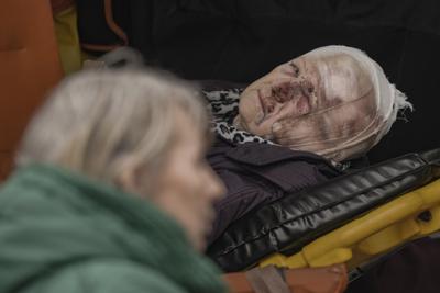 An injured woman evacuated from Irpin lies on a stretcher in an ambulance on the outskirts of Kyiv, Ukraine, Saturday, March 26, 2022. Russia continues to pound cities throughout Ukraine — explosions rang out Saturday near the western city of Lviv, a destination for refugees that has been largely spared from major attacks. (AP Photo/Vadim Ghirda)