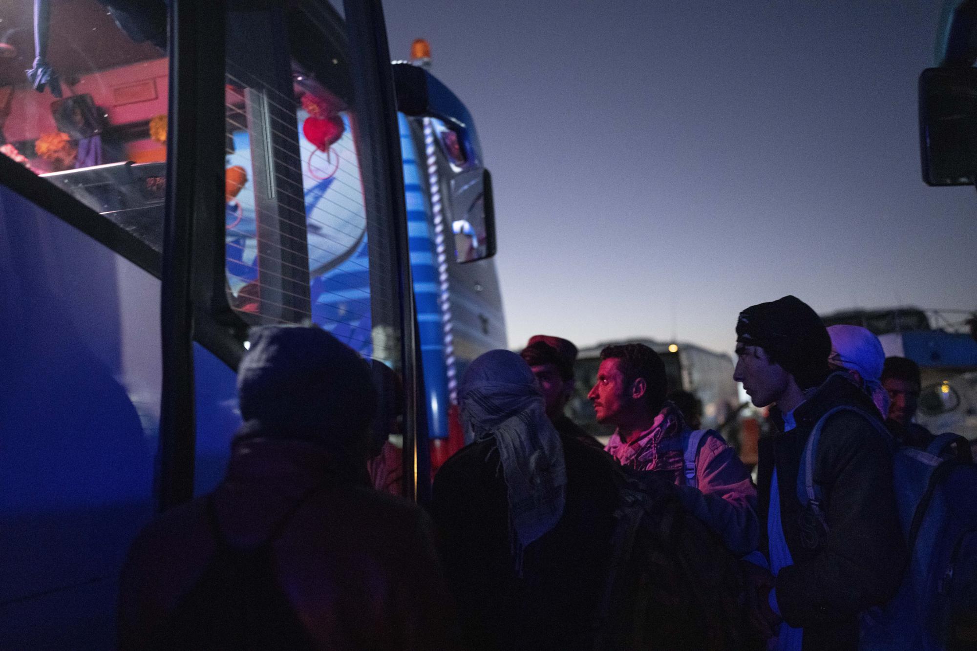 Afghan men board a bus in Herat, Afghanistan, Tuesday , Nov. 23, 2021, for a 300-mile trip south to Nimrooz near the Iranian border. Afghans are streaming across the border into Iran, driven by desperation after the near collapse of their country's economy following the Taliban's takeover in mid-August. In the past three months, more than 300,000 people have crossed illegally into Iran, according to the Norwegian Refugee Council, and more are coming at the rate of 4,000 to 5,000 a day. (AP Photo/Petros Giannakouris)