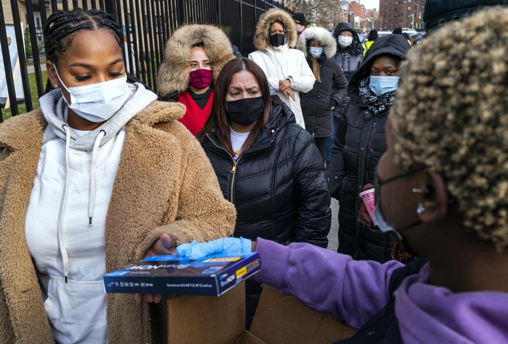 FILE - People line up and receive test kits to detect COVID-19 as they are distributed in New York on Dec. 23, 2021. More than a year after the vaccine was rolled out, new cases of COVID-19 in the U.S. have soared to their highest level on record at over 265,000 per day on average, a surge driven largely by the highly contagious omicron variant. (AP Photo/Craig Ruttle, File)