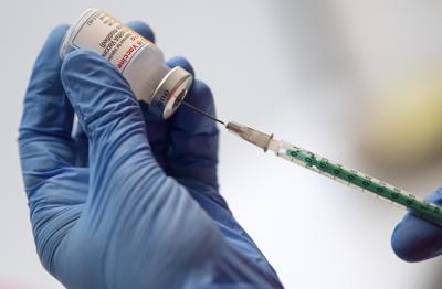 Personal médico de la organización de ayuda Malteser prepara jeringas con la vacuna de Moderna contra el coronavirus en un autobús de vacunación en Unterschleissheim, Alemania, el jueves 18 de noviembre de 2021. (Sven Hoppe / dpa vía AP)