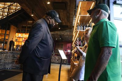 ARCHIVO - Un empleado de seguridad observa un teléfono celular que una pareja le muestra para mostrarle que están vacunados a fin de ingresar en el establecimiento City Winery, en Nueva York, el jueves 24 de junio de 2021. (AP Foto/Frank Franklin II, Archivo)