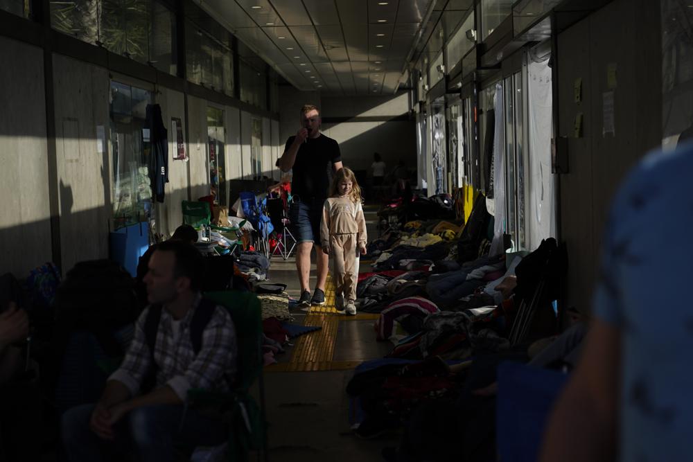 Refugiados ucranianos esperan en una parada de autobús cerca de la frontera después de llegar el lunes 4 de abril de 2022 a Tijuana, México, mientras buscan una forma de solicitar asilo en los Estados Unidos.  Cientos de refugiados ucranianos que llegan a diario tienen un mensaje para familiares y amigos en Europa: la ruta más rápida para establecerse en Estados Unidos es reservar un vuelo a México.  (Foto AP/Gregory Bull)