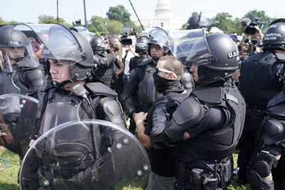 Varios policías rodean a un hombre (al centro, con anteojos) durante un mitin cerca del Capitolio de Estados Unidos el sábado 18 de septiembre de 2021, en Washington, D.C. (AP Foto/Gemunu Amarasinghe)