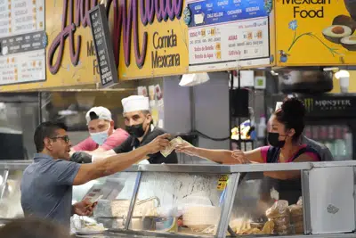 FILE - Money is exchanged at a food stand inside Grand Central Market on Wednesday, July 13, 2022, in Los Angeles. U.S. inflation, an economic afterthought for decades, returned in 2022 with the relentless rise in prices devouring workers' pay and putting American consumers in a foul mood. (AP Photo/Marcio Jose Sanchez, File)