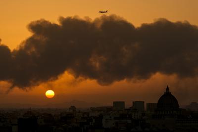 A passenger airplane flies over a smoldering fire at a Saudi Aramco oil depot after a Yemen Houthi rebel attack the day before ahead of a Formula One race as the sun rises in Jiddah, Saudi Arabia, Saturday, March 26, 2022. (AP Photo/Hassan Ammar)