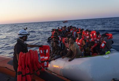 Crew of the Sea-Watch 3 distribute life jackets to 108 people in a boat in distress in the central Mediterranean on Saturday, July 23, 2022. Ships in the Mediterranean Sea have rescued over 1,100 people struggling to reach Europe in rickety smugglers boats and found five bodies. The Italian Coast Guard says Sunday that Italian vessels recovered the bodies Saturday as it rescued 674 people packed on a fishing boat adrift in the Mediterranean off the Libyan coast. (Nora Boerding/Sea-Watch via AP)