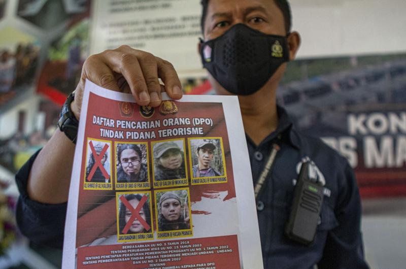 A police officer shows a wanted poster displaying the photos of two militants Ali Kalora, top left, and Jaka Ramadan, bottom left, who were killed during shootout with security forces, during a press conference at the Parigi Moutong Police Station in Parigi Moutong district, Central Sulawesi, Indonesia, Sunday, Sept. 19, 2021. Indonesia's most wanted militant with ties to the Islamic State group was killed Saturday in a shootout with security forces, the Indonesian military said, in a sweeping counterterrorism campaign against extremists in the remote mountain jungles. (AP Photo/Mohammad Taufan)