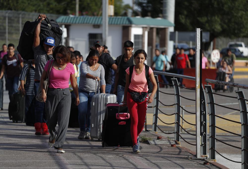 ARCHIVO - Un grupo de trabajadores mexicanos con empleos estacionales esperándoles en Estados Unidos caminan con su equipaje por el puente internacional Puerta México hacia Brownsville, Texas, en Matamoros, estado de Tamaulipas, México, el 27 de junio de 2019. Las remesas que llegan a México - el dinero que envían los migrantes a sus familiares en casa- se han disparado en los dos últimos años, y se espera que alcancen los 50.000 millones de dólares por primera vez cuando se contabilicen las cifras de 2021. Eso superaría casi todas las otras fuentes de divisas en México. (AP Foto/Rebecca Blackwell, Archivo)