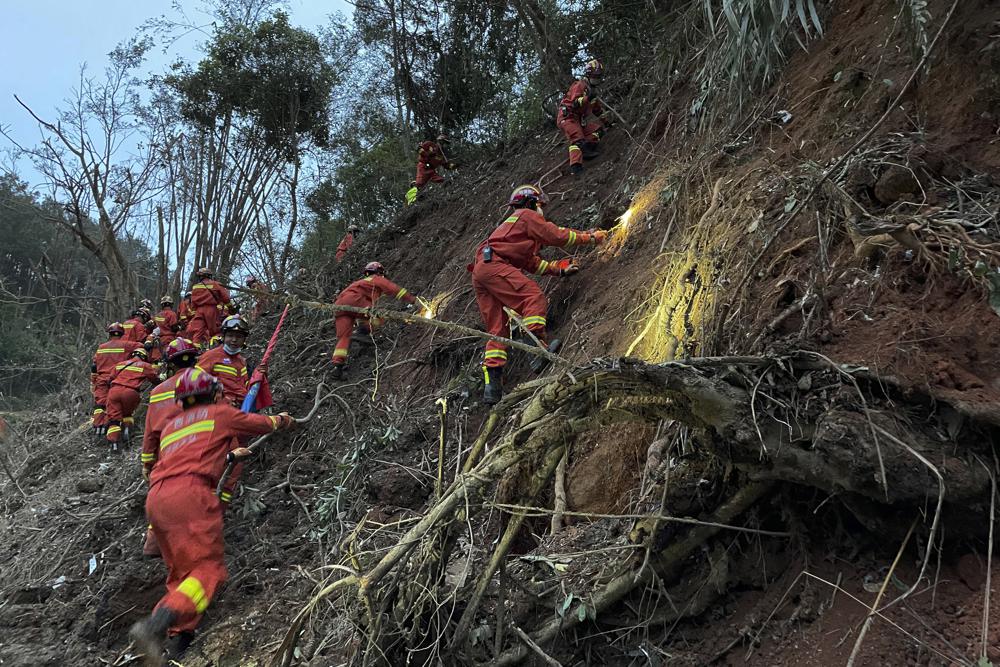 En esta foto publicada por la Agencia de Noticias Xinhua, los rescatistas realizan operaciones de búsqueda en el lugar de un accidente aéreo en el condado de Tengxian, en la región autónoma de la etnia zhuang de Guangxi, en el sur de China, el martes 22 de marzo de 2022. Billeteras manchadas de barro.  tarjetas bancarias  Tarjetas de identidad oficiales.  Algunos de los efectos personales de 132 vidas presuntamente perdidas fueron alineados por rescatistas que recorrieron una montaña remota el martes en busca de los restos de un avión de China Eastern que un día antes cayó inexplicablemente del cielo y estalló en una enorme bola de fuego.  (Zhou Hua/Xinhua vía AP)