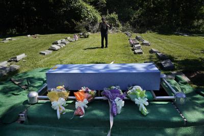 Siva Sriskanda toma fotos del féretro de James Brown, un amigo y empleado, luego de un breve servicio funerario en un cementerio en Staten Island, Nueva York, el jueves 17 de junio de 2021. (AP Foto/Seth Wenig)