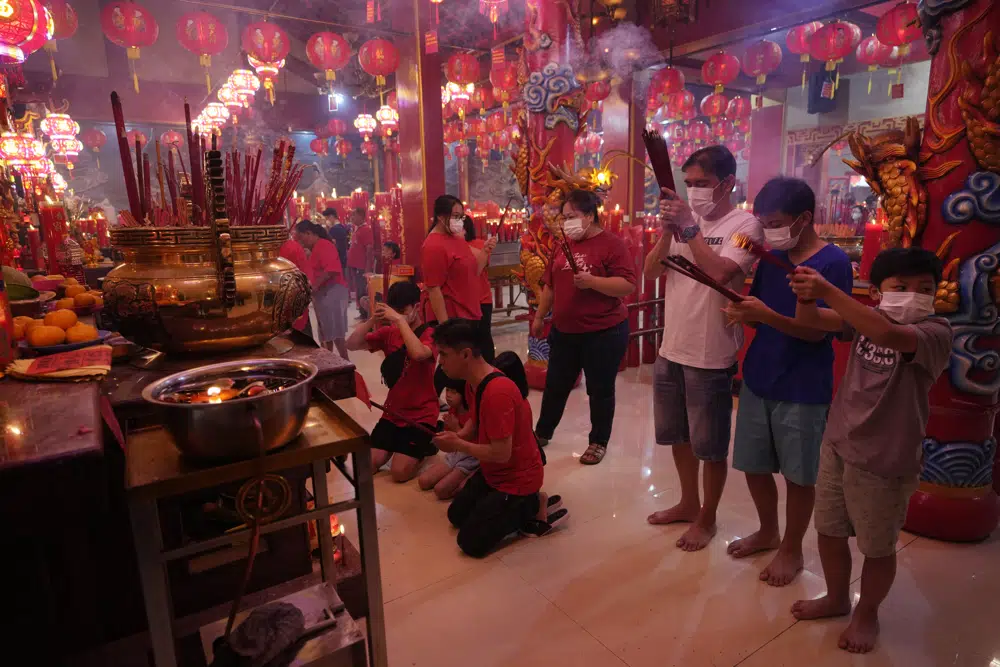 Fieles con mascarillas ofrecen plegarias en el Templo Hok Lay Kiong en Bekasi, Indonesia, el domingo 22 de enero de 2023. El Año Nuevo Lunar daba inicio al Año del Conejo según el zodiaco chino. (AP Foto/Achmad Ibrahim)