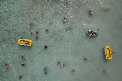 La gente nada y juega con botes en el Cayo Playuela del Parque Nacional Morrocoy, estado Falcón, Venezuela, el domingo 13 de junio de 2021. (AP Foto/Matias Delacroix)