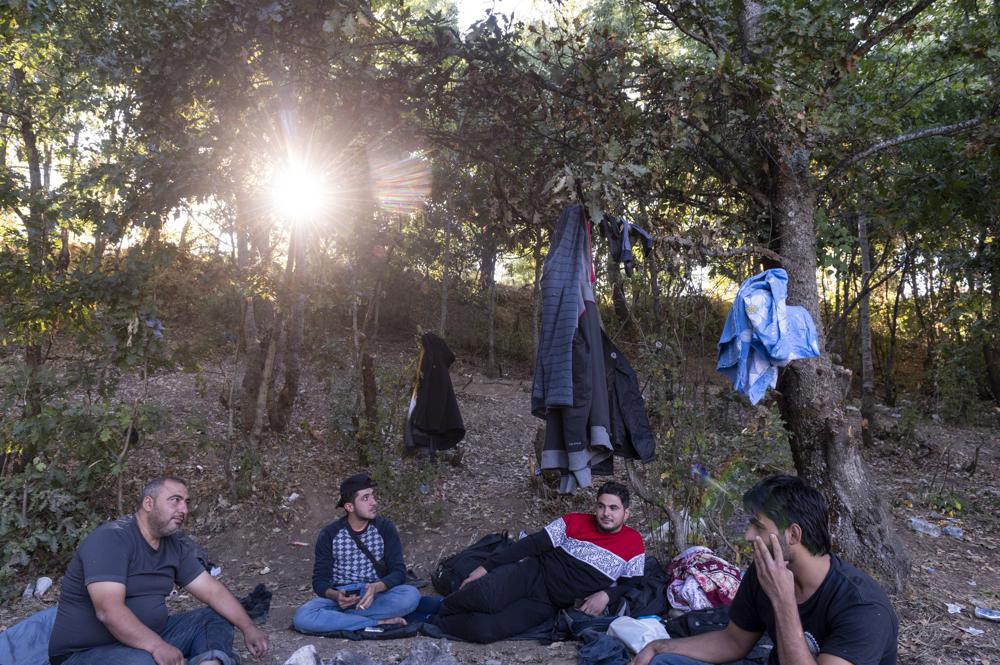 Syrian migrants sit inside a forest near Ieropigi village, northern Greece, at the Greek - Albanian border, on Saturday, Sept. 25, 2021. A relatively smooth section of Greece's rugged border with Albania is turning into a major thoroughfare north for migrants in Greece seeking a better life in Europe's prosperous heartland. (AP Photo/Giannis Papanikos)