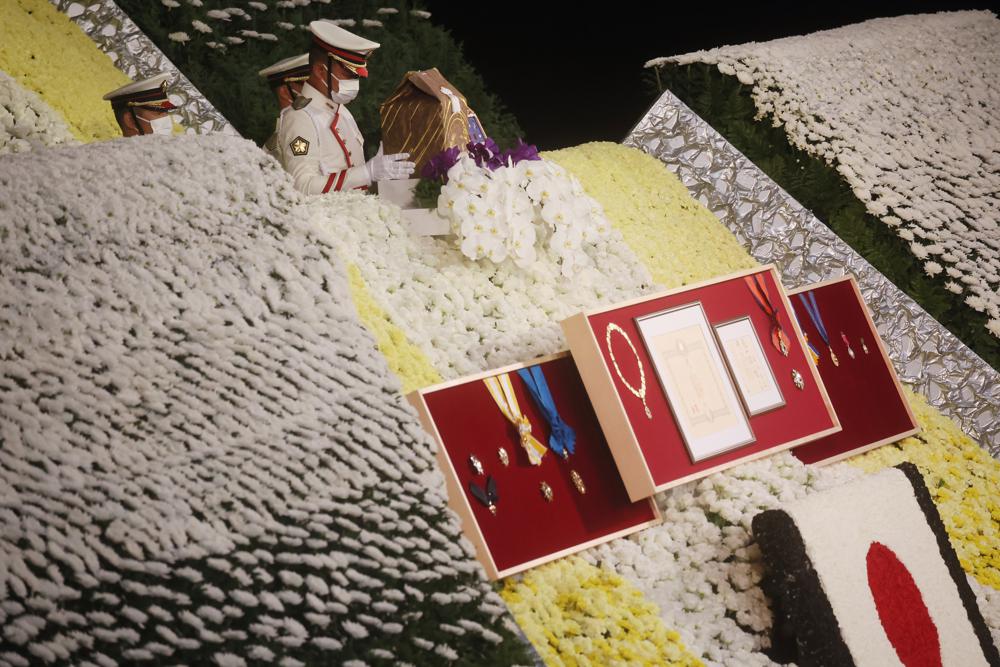 Former Prime Minister Shinzo Abe's urn is on top of a wall of flowers at his state funeral, Tuesday, Sept. 27, 2022, in Tokyo. Abe was assassinated in July. (Leah Millis/Pool Photo via AP)