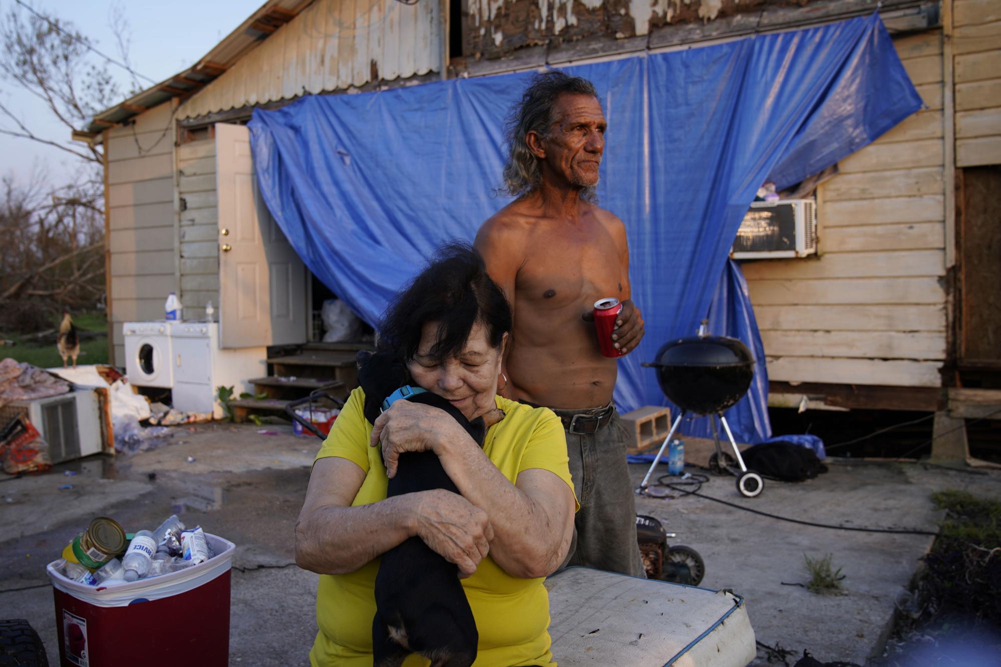 FILE - Yvonne Lacobon hugs a dog beside Tommy Williams at Williams' home damaged by Hurricane Ida, Saturday, Sept. 4, 2021, in Dulac, La. The United Nations on Monday, Feb. 28, 2022, released a new report on climate change. (AP Photo/John Locher, File)