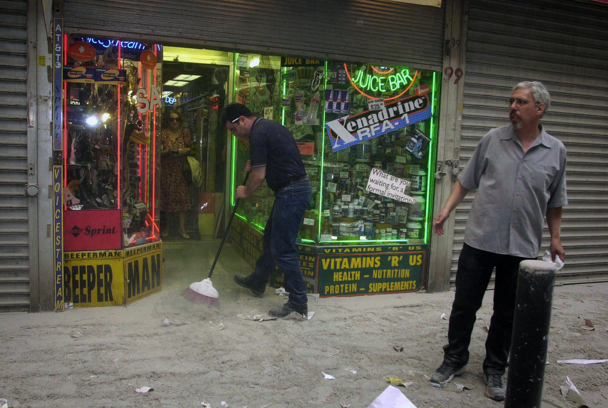 Harry Shasho sweeps up before being evacuated from his vitamin store after the collapse of New York's World Trade Center on Tuesday, Sept. 11, 2001. (AP Photo/Suzanne Plunkett)