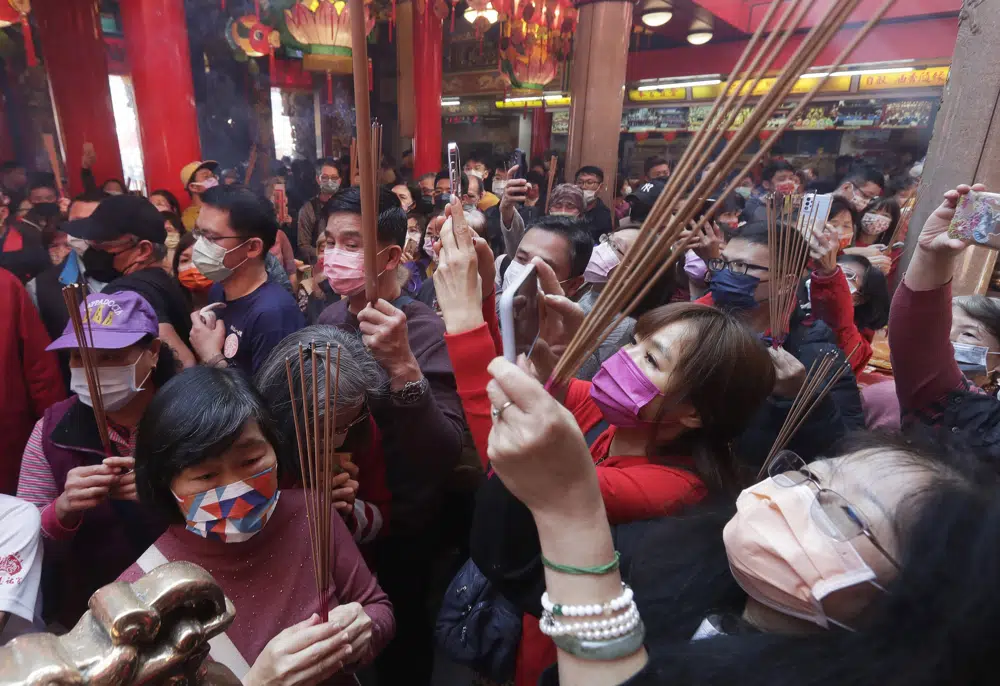 Fieles con mascarillas para evitar contagios de coronavirus rezan en un templo el primer día del Año Nuevo Lunar en Taipéi, Taiwán, el domingo 22 de enero de 2023. Cada año lleva el nombre de uno de los 12 signos del zodiaco chino, en un ciclo que se repite, y el que comienza es el Año del Conejo. (AP Foto/Chiang Ying-ying)