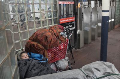 Archivo - Una persona sin hogar duerme debajo de mantas junto a un carrito de compras lleno de pertenencias en una estación del metro de Nueva York, el 9 de enero de 2018. El alcalde de Nueva York, Eric Adams, anunció un plan el viernes 18 de febrero de 2022 para evitar que los indigentes duerman en los trenes o vivan en las estaciones. (Foto AP/Mark Lennihan, Archivo)
