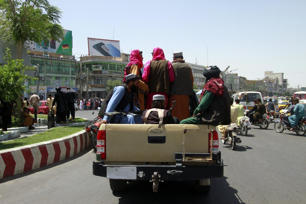 Taliban fighters sit on the back of a vehicle in the city of Herat, west of Kabul, Afghanistan, Saturday, Aug. 14, 2021, after they took this province from Afghan government. The Taliban seized two more provinces and approached the outskirts of Afghanistan's capital. (AP Photo/Hamed Sarfarazi)